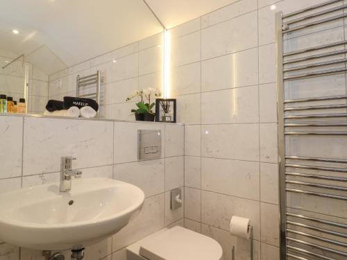 a white bathroom with a sink and a toilet at Meadow Syke Barn in Penrith