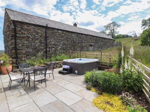 a patio with a table and a hot tub at Meadow Syke Barn in Penrith