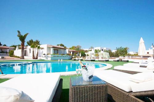 a swimming pool with white chairs and a bottle of wine at Residencial Bogamarí in San Antonio Bay