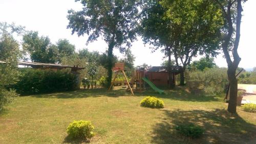 a yard with a playground with a tree and a swing at Villa Monnalisa in Pian di Scò