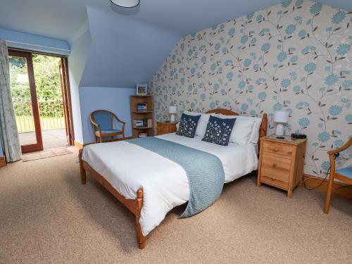 a bedroom with a bed with a blue wall at Henblas Cottage in Abergele