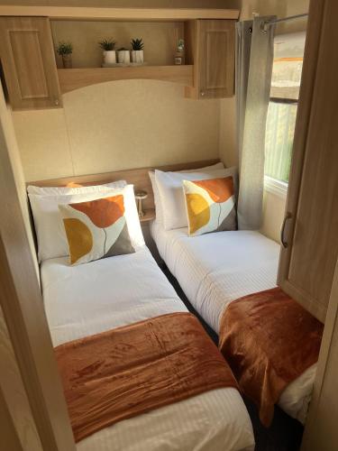 two twin beds in a small room withacers at Hornshole Hideaway Caravan Hawick in Hawick