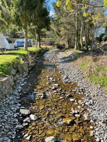 a river with rocks and trees and cars parked at Hornshole Hideaway Caravan Hawick in Hawick