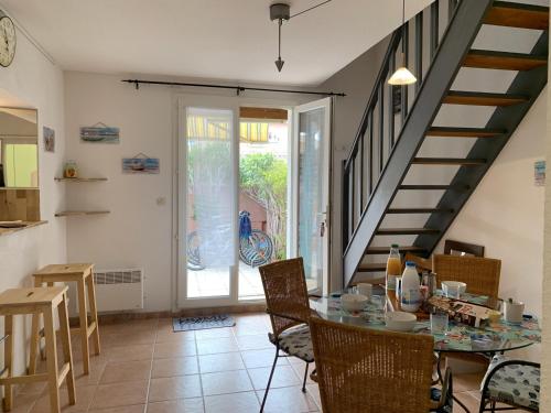 une cuisine et une salle à manger avec une table et un escalier dans l'établissement Villa Confortable 6 Pers. Climatisée, Proche Plage du Grazel, Calme, Tout Équipée, Stationnement Inclus - FR-1-796-71, à Gruissan