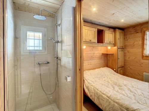 Un pequeño dormitorio con ducha y cama. en Chalet cosy 2 étoiles, 9 pers, 4 ch, 2 sdb, terrasse sud, proche télésiège, commerces, piscine été - FR-1-417-5, en La Toussuire