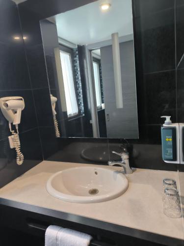 a bathroom with a sink and a mirror at Brit Hotel Porte d'Espagne in Perpignan