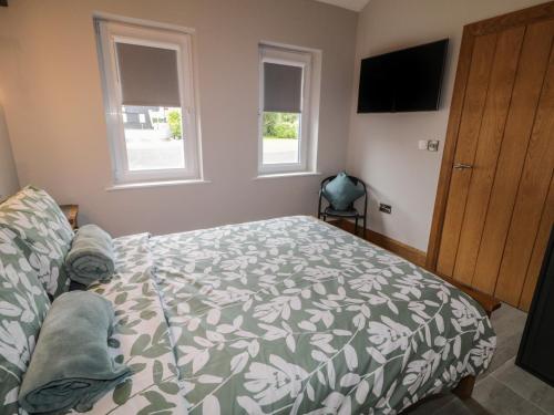 a bedroom with a bed and a television and two windows at Mountain View in Limavady