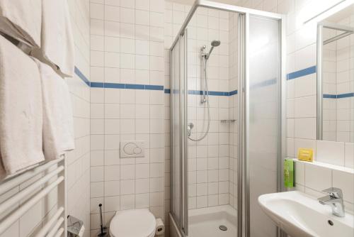 a bathroom with a shower and a toilet and a sink at JUFA Hotel Kaprun - Summercard included in Kaprun