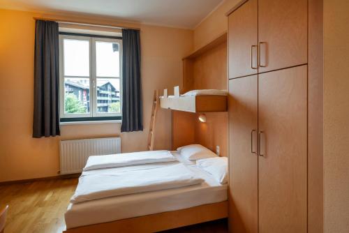 a bedroom with a bed and a cabinet and a window at JUFA Hotel Kaprun - Summercard included in Kaprun