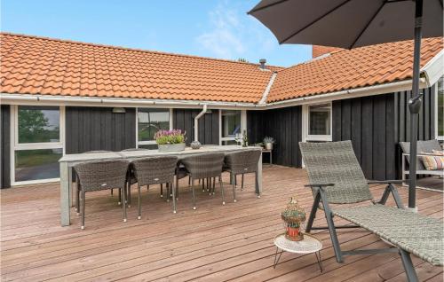 a wooden deck with a table and chairs and an umbrella at Gorgeous Home In Oksbøl With Sauna in Oksbøl