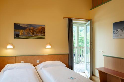 two beds in a hotel room with a window at JUFA Hotel Kaprun - Summercard included in Kaprun
