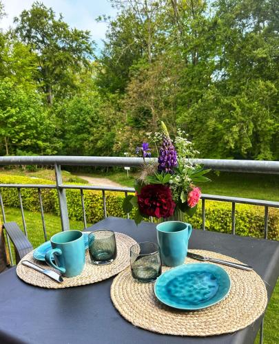 a table with two plates and cups and a vase of flowers at Kunst küsst Küste in Hohwacht