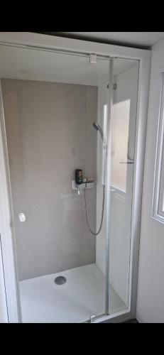 une douche avec une porte vitrée dans une salle de bain dans l'établissement Mobil Home Camping 4*, à Gastes