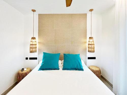 a bedroom with a white bed with blue pillows at Residencial Bogamar&iacute; in San Antonio Bay