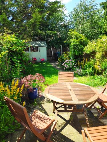 a wooden table and chairs in a yard at Stylish Victorian House in Watford