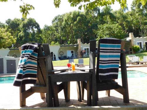 a table and two chairs with towels on them next to a pool at Lodge Azure in Port Edward