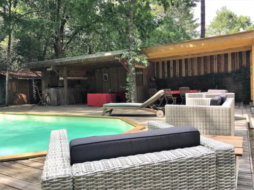 - une piscine avec des meubles en osier à côté d'une maison dans l'établissement Cap Ferret Villa Grand Chalet Bois, à Lège-Cap-Ferret