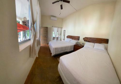 a bedroom with two beds and a window at Casa Piedra de Agua Bacalar in Bacalar