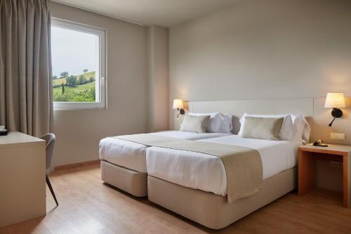 a bedroom with a large white bed with a window at Hotel Sukha in Escoriaza