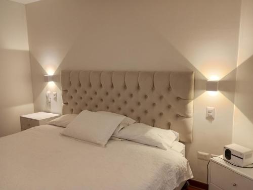 リマにあるEL PRAT Luxury Aparment Lima Peruのベッドルーム1室(白い大型ベッド1台、照明2つ付)