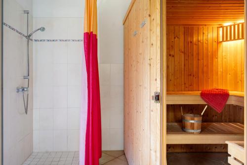 a shower with a red curtain in a bathroom at Ferienhaus Seeschwalbe in Munkbrarup