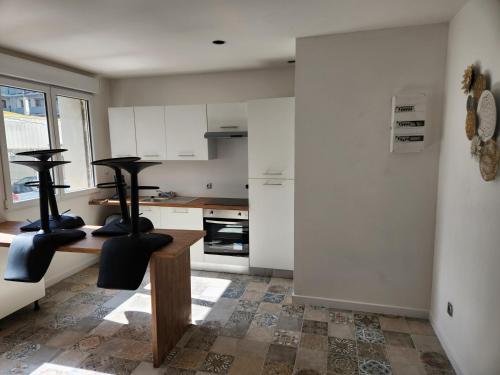 une cuisine avec des armoires blanches et une table et des chaises dans l'établissement T3 Cosy, à Saint-Étienne