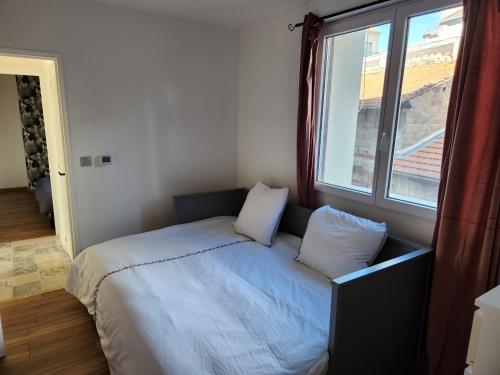 - un lit avec deux oreillers dans une chambre dotée d'une fenêtre dans l'établissement T3 Cosy, à Saint-Étienne