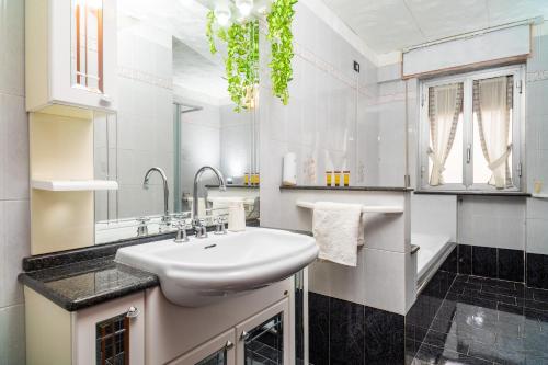 Un baño blanco con lavabo y espejo. en La Casa Di Jano, en Francavilla di Sicilia