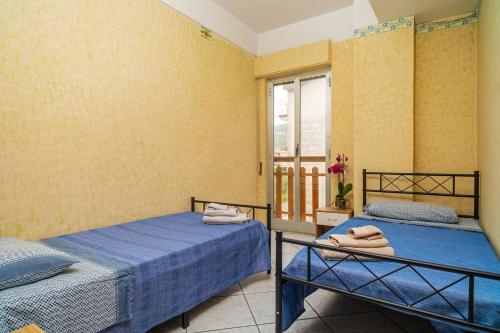 Dos camas en una habitación con ventana. en La Casa Di Jano, en Francavilla di Sicilia