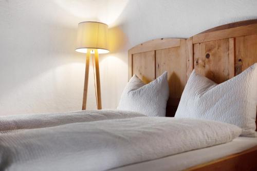 a bedroom with a bed with white sheets and a lamp at Ansitz Baumannhof Apt Mitte in Falzes