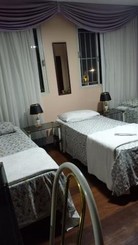a hotel room with two beds and two windows at Kzazendf Cama&Cafe Hospedagem Familiar in Brasilia
