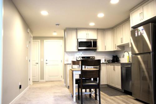 a kitchen with white cabinets and a black refrigerator at Like cozy place in Calgary
