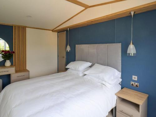 a bedroom with a large white bed with blue walls at Hazel Lodge in Whitby