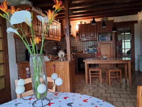 un vase avec des fleurs sur une table dans une cuisine dans l'établissement la maison du sabotier, à Jars