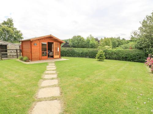 a small wooden cabin in a grassy yard at Loanview in Cornhill-on-tweed