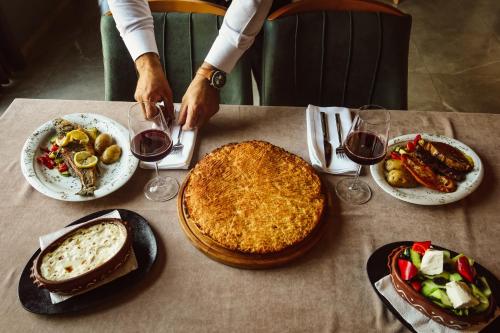 a person is cutting a pie on a table with wine glasses at Andoena Resort in Lipjan