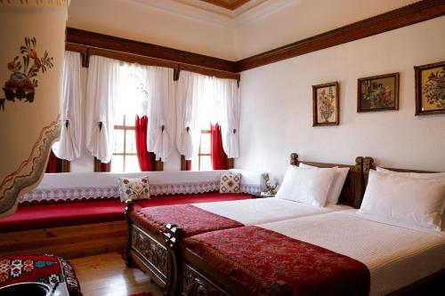 a bedroom with a bed and windows with red curtains at Boutique Hotel Musée in Gjirokastër