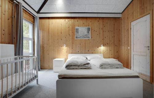 a bedroom with a white bed and wooden walls at Nice Home In Ebeltoft With Kitchen in Ebeltoft