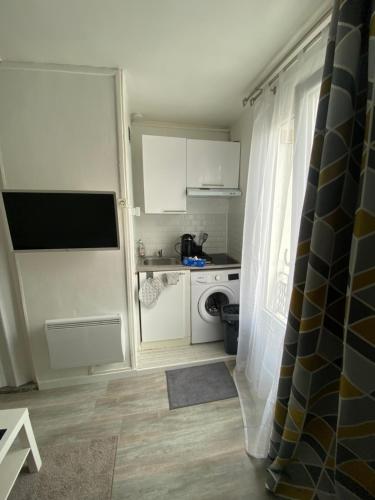 Elle comprend une petite cuisine avec des placards blancs et un lave-linge/sèche-linge. dans l'établissement Studette 13m2, à Bagnolet