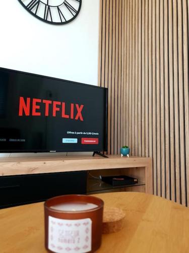 une télévision sur une table avec une horloge sur le mur dans l'établissement Le Royal George - Appartement 4 pers, à Amboise