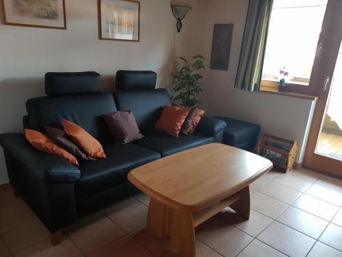 ein Wohnzimmer mit einem blauen Sofa und einem Holztisch in der Unterkunft Ferienhaus in ruhiger Lage, mit Balkon und großer Terrasse in Aschau im Chiemgau