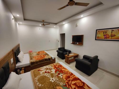 a room with a bed and two chairs and a tv at Alaknanda Motel & Restaurant in Rudraprayāg