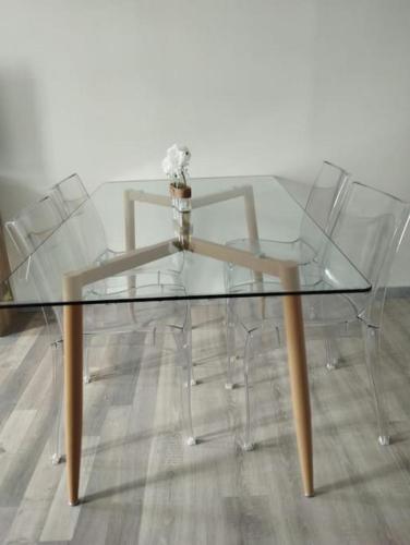une table en verre avec deux chaises et un vase dans l'établissement La Suite Aushayna, à Amiens
