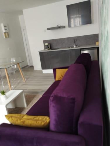 - un canapé violet dans le salon avec une table dans l'établissement La Suite Aushayna, à Amiens