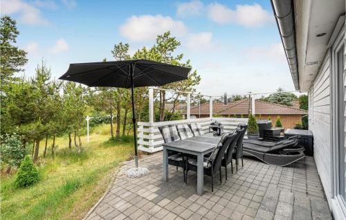 a table and chairs with an umbrella on a patio at Holiday Home Rømø 58 in Rømø Kirkeby