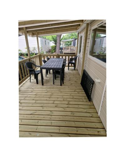 une terrasse avec une table de pique-nique et des chaises sur une maison dans l'établissement Mobil Home Camping 4*, à Gastes