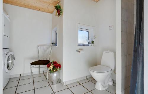 a white bathroom with a toilet and a chair at Pet Friendly Home In Knebel With Sauna in Skødshoved Strand