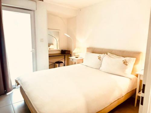 un lit blanc dans une chambre avec une fenêtre dans l'établissement Modern Bright Cannes Apt 2 min walk to the Beach, à Cannes