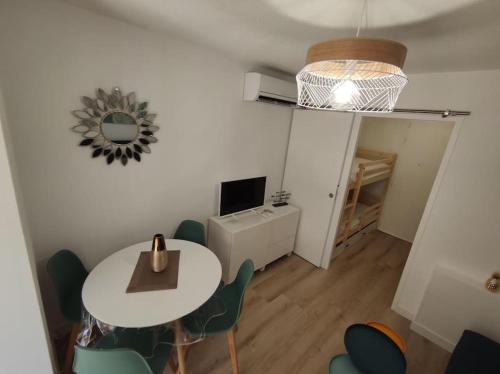 un salon avec une table, des chaises et une télévision dans l'établissement Super logement pour 4 avec SPA privé, plages à proximité, piscine et jardin, à Sausset-les-Pins