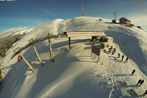 a snow covered mountain with people on a ski slope at Lux Garden Hotel in Azuga